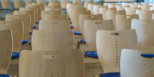 Stuhlreihen einer Konferenz stehen hintereinander. 