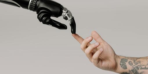 Eine Roboterhand und eine menschliche Hand berühren sich mit einem Finger.