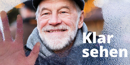 Motivbild der Woche des Sehens 2024. Ein älterer Mann hält seine Hand gegen eine Scheibe, die nur zum Teil klar ist.