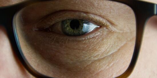 Ein Auge. Davor ein Brillenglas. 