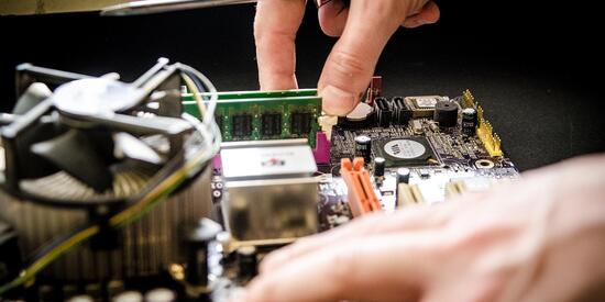 Zwei Hände die in einem offenen Computer etwas reparieren 